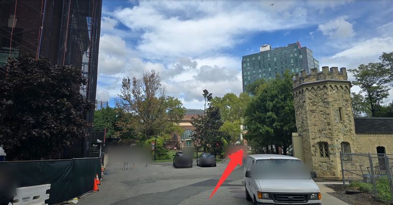 Campus road outside Babbio with a stone gatehouse on the right; a red arrow points ahead