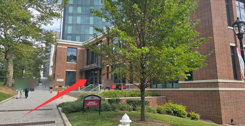 Brick University Center building with its sign; a red arrow points to the entrance