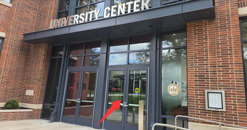Glass doors under the University Center sign; a red arrow points to the right-hand doors